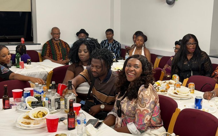 Igbo Union Northamptonshire - Members seated along a long table with food and drinks at a community gathering