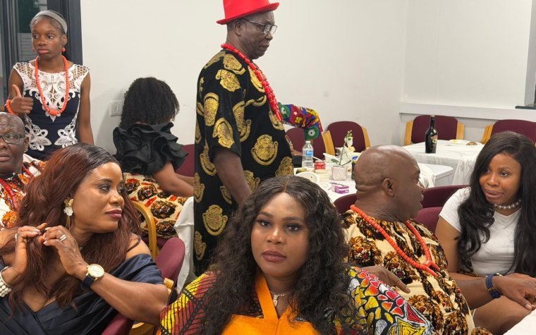 Igbo Union Northamptonshire - Members in Igbo dress at a gathering, one standing in a red cap and patterned robe