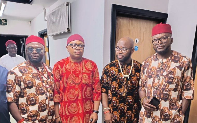 Igbo Union Northamptonshire - A group of men in Igbo dress and red caps gathered together indoors
