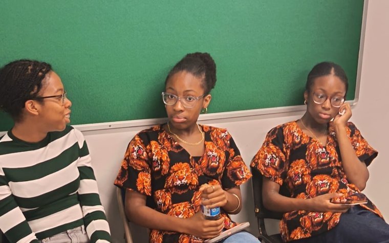 Igbo Union Northamptonshire - Three young members seated together, two in matching Igbo print