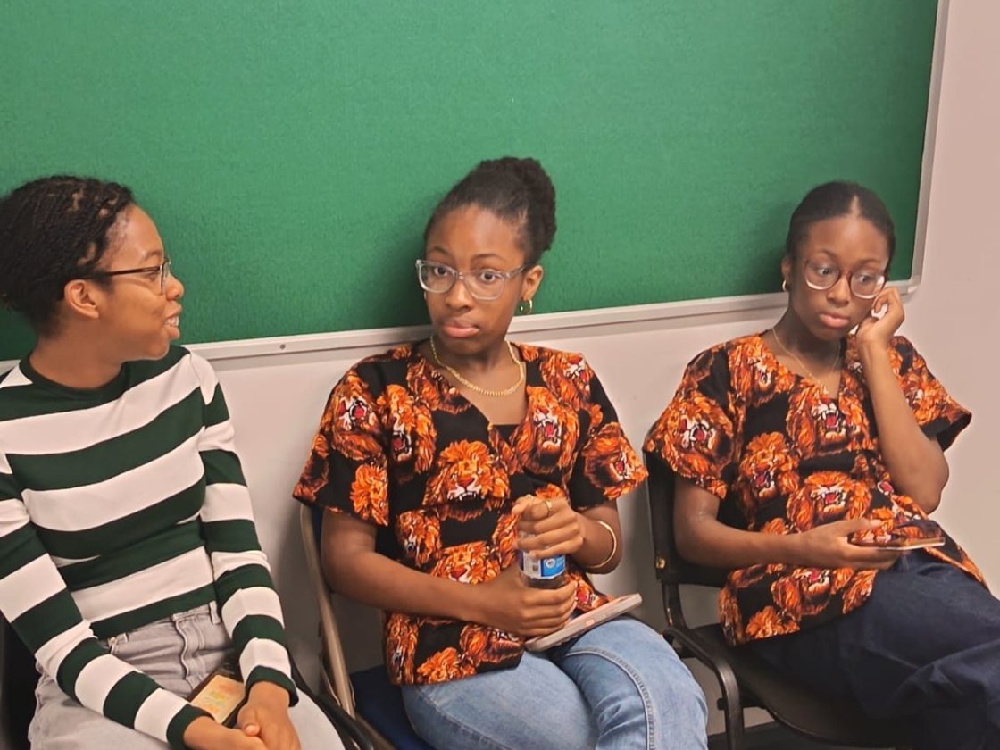 Igbo Union Northamptonshire - Three young members seated together, two in matching Igbo print